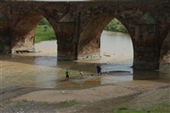 Δύο από τις πελώριες κεντρικές καμάρες της μεσαιωνικής γέφυρας Τσομπάν στον Αράξη και τέσσερις ψαράδες