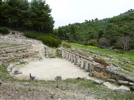 Αμφιάρειο: Το ελληνιστικό Θέατρο του Ιερού (γενική άποψη, λήψη από τη ΒΔ πλευρά του κοίλου) και η Μεγάλη Στοά (στο βάθος δεξιά)